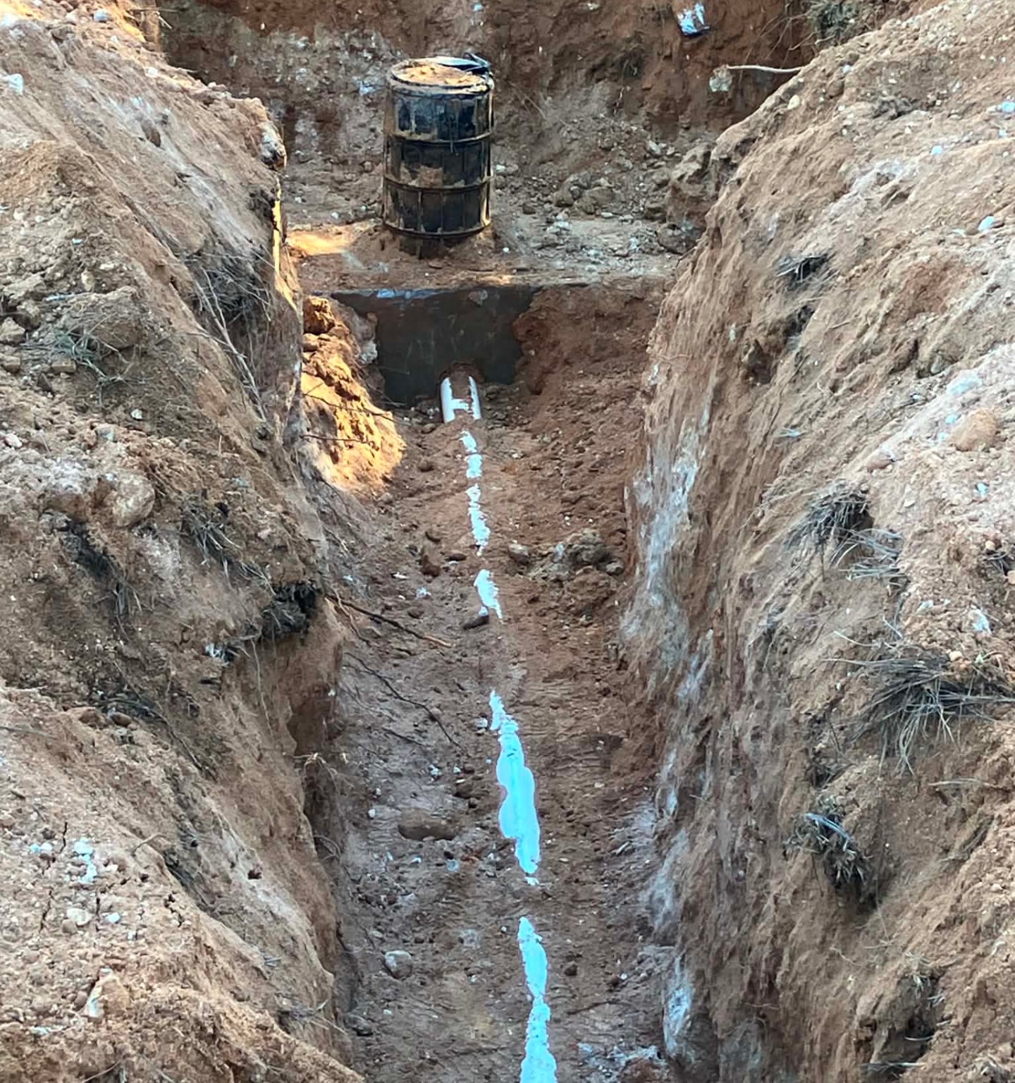 A deep excavation with the new blue force main run along the trench bottom