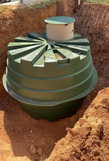An Orenco treatment tank set in an excavated red-clay pit at an EMS install site
